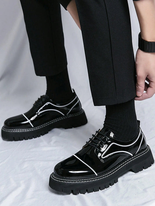 Black glossy shoes with white accents worn by a person on a light gray background