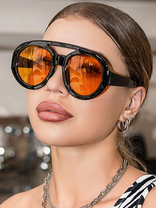 Close-up of a person wearing large black sunglasses with orange lenses.