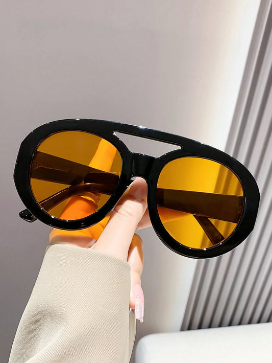 Sunglasses with yellow lenses and black frames held by a hand against a neutral background