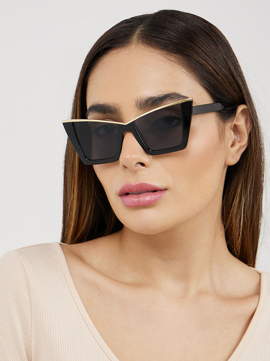 Woman wearing black cat-eye sunglasses against a light background