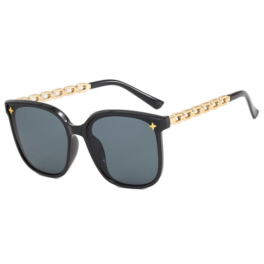 Black sunglasses with gold chain design on a white background