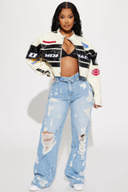 Woman wearing a colorful jacket and ripped jeans on a white background