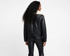 Person wearing a black leather jacket and pants on a white background