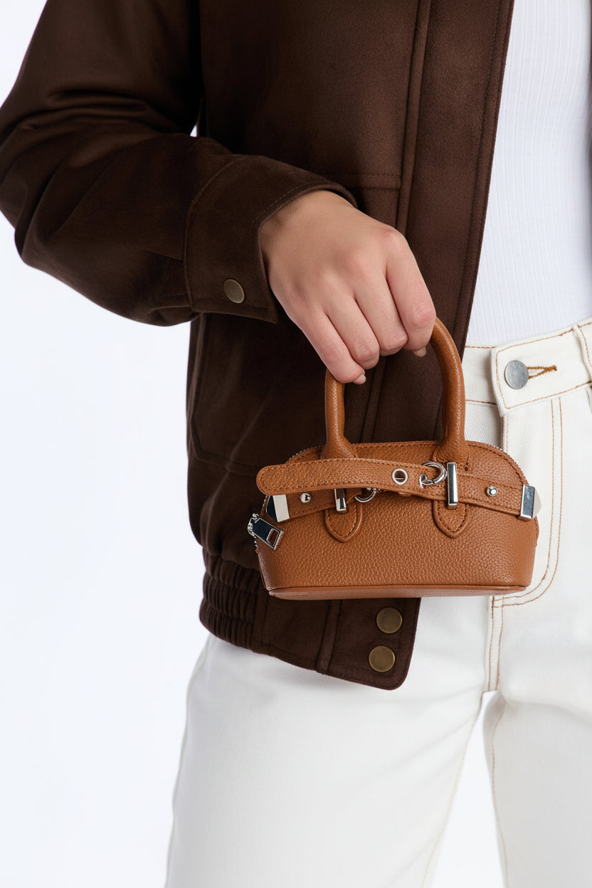 Person holding a brown handbag with a white background