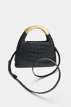 Black crocodile-patterned handbag with a gold handle on a white background