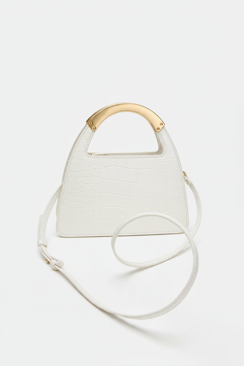 White handbag with a gold handle on a light gray background
