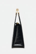 Black handbag with gold handles on a white background