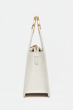 white handbag with gold handles on a  backgrounde 