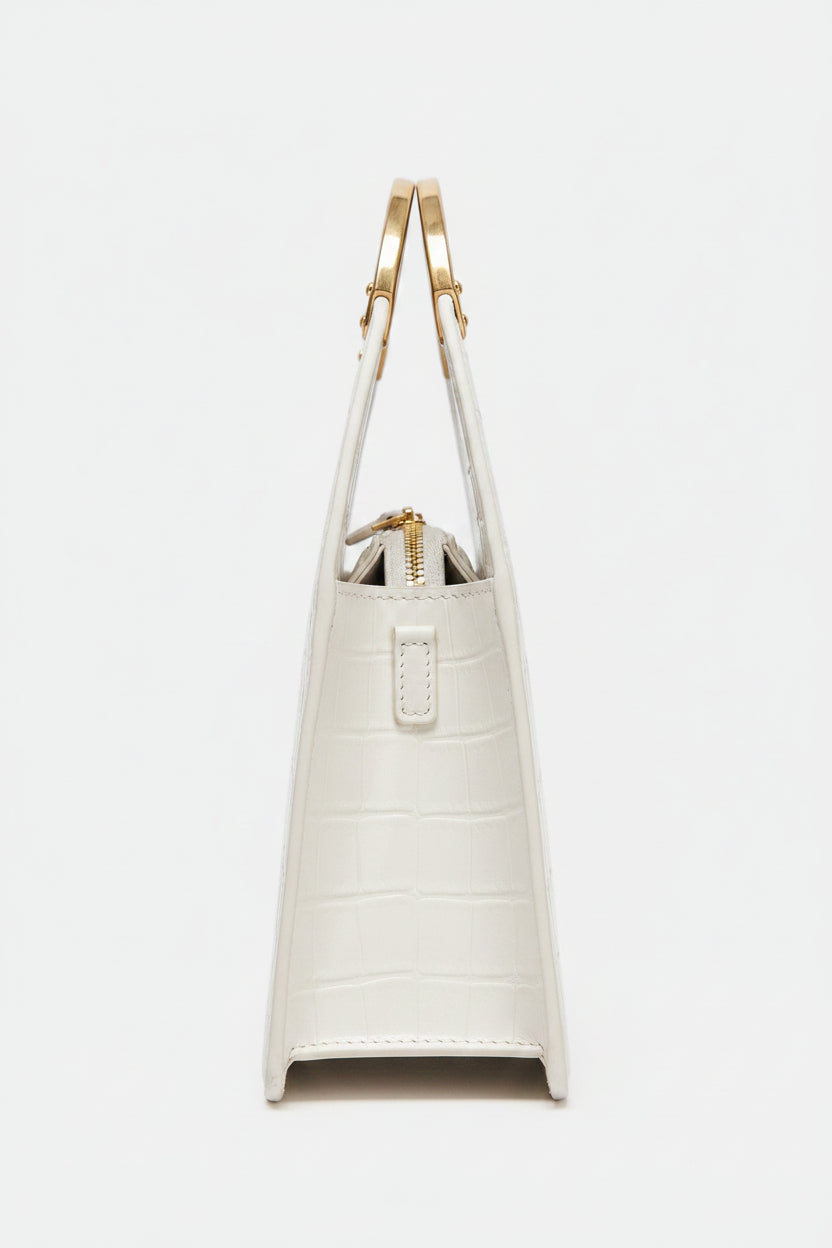 white handbag with gold handles on a  backgrounde 