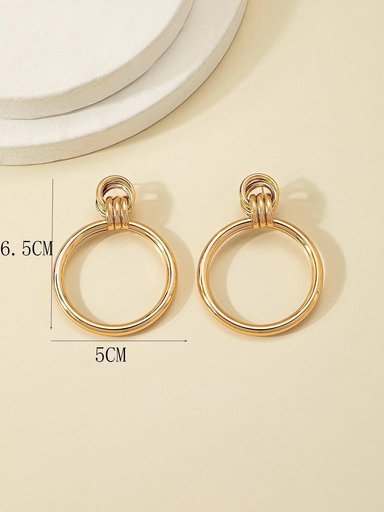 Gold hoop earrings on a beige background with measurements indicated.