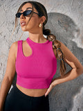 Woman wearing a bright pink crop top against a textured gray wall.