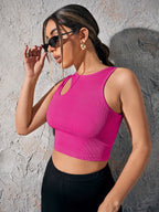 Woman wearing a bright pink crop top against a textured wall.