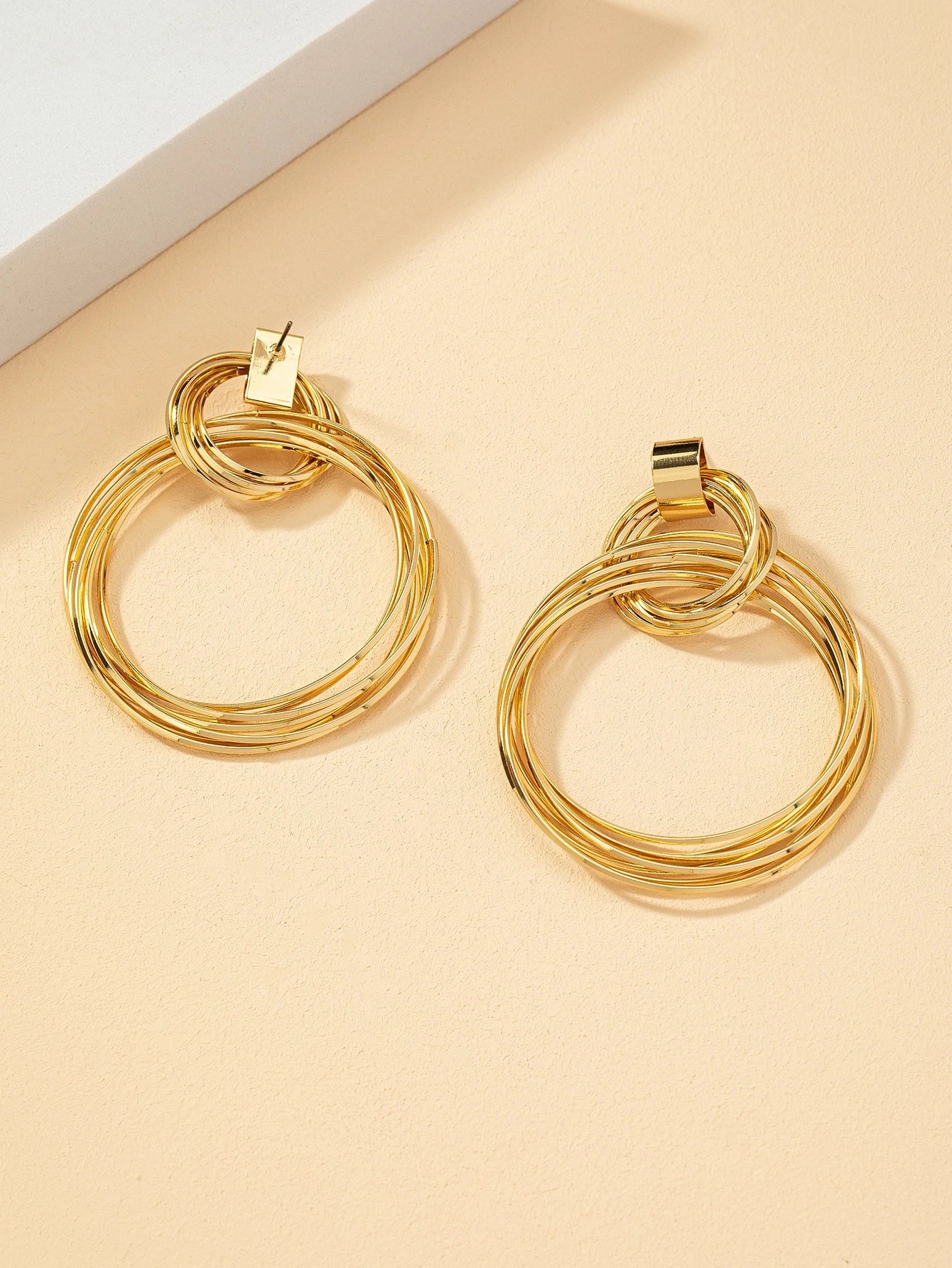 FAVEN Gold hoop earrings on a beige background
