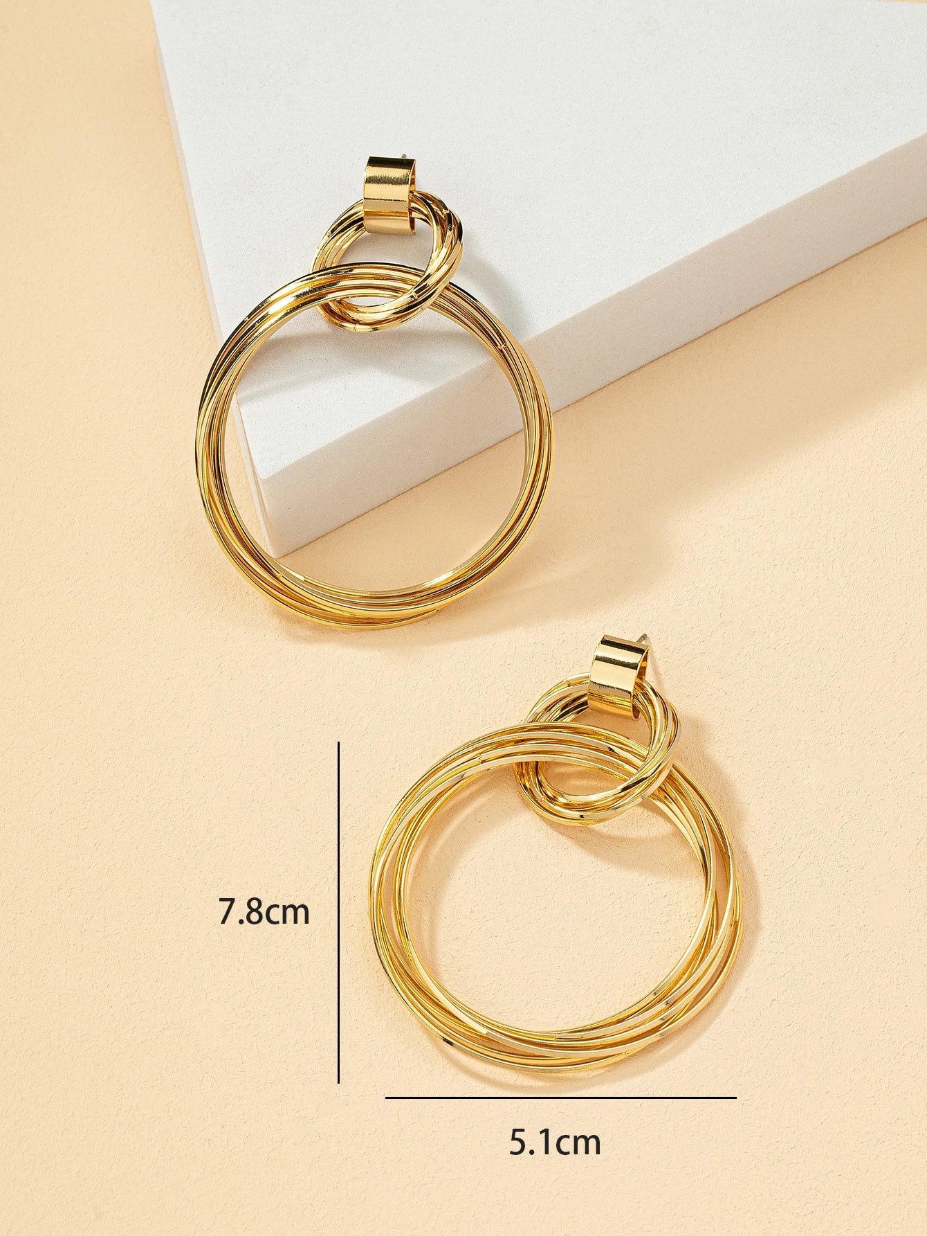 FAVEN Gold hoop earrings on a beige background