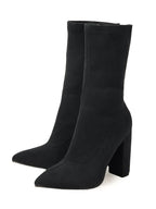 Black knee-high boots with a block heel on a white background