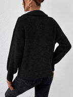 Person wearing a black knitted sweater and black pants against a white background