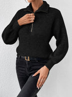 Person wearing a black knitted sweater and black pants against a white background