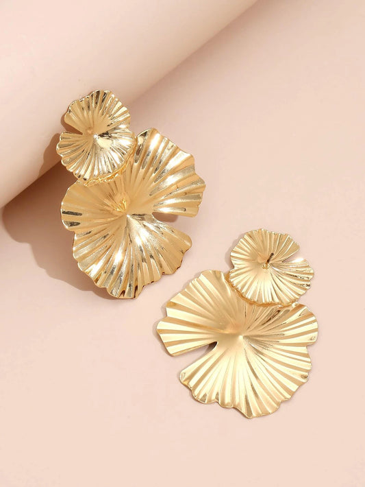 Gold shell-shaped earrings on a light pink background
