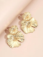 Gold leaf-shaped earrings on a light pink background