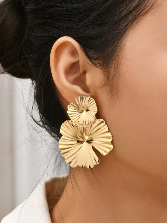 Gold earrings worn by a person with a neutral background