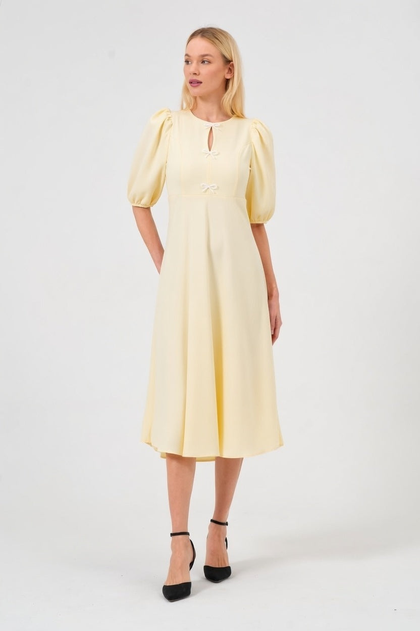 Woman wearing a yellow dress with puff sleeves on a white background