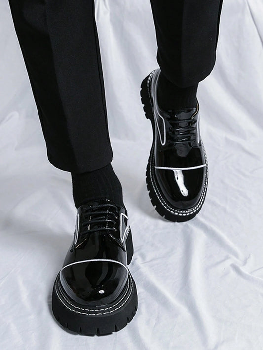 Black glossy shoes worn with black pants on a white background