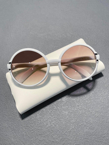 White sunglasses with brown lenses on a gray surface