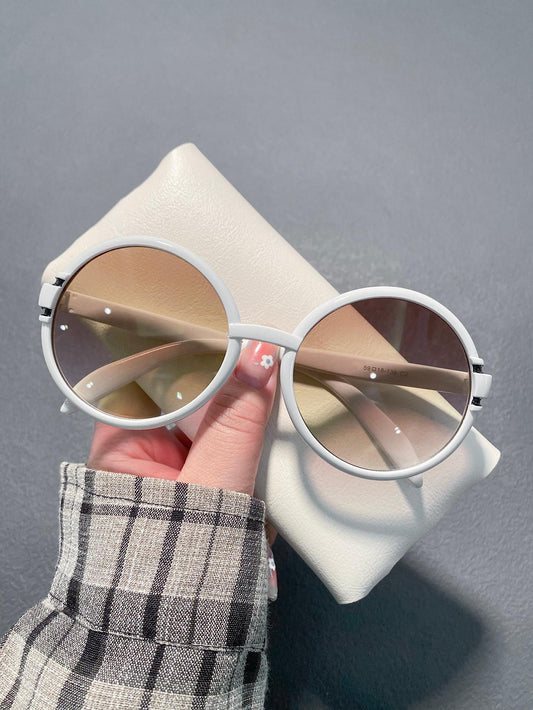 White sunglasses held by a hand with a gray background