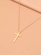 Gold cross necklace on a pink background