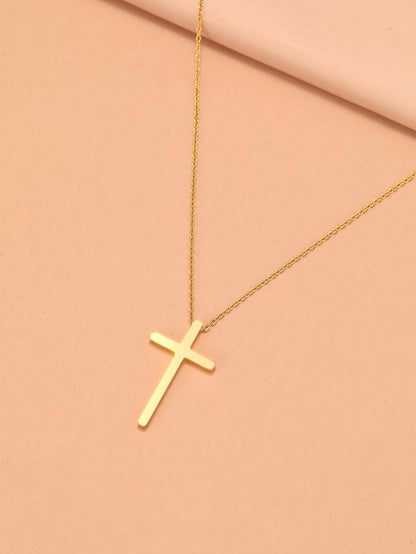Gold cross necklace on a pink background
