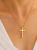 Gold cross necklace on a person wearing a white top