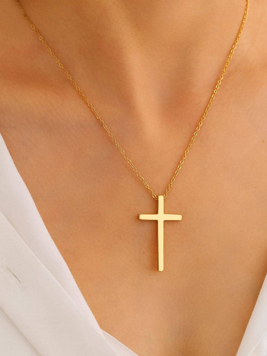 Gold cross necklace on a person wearing a white top