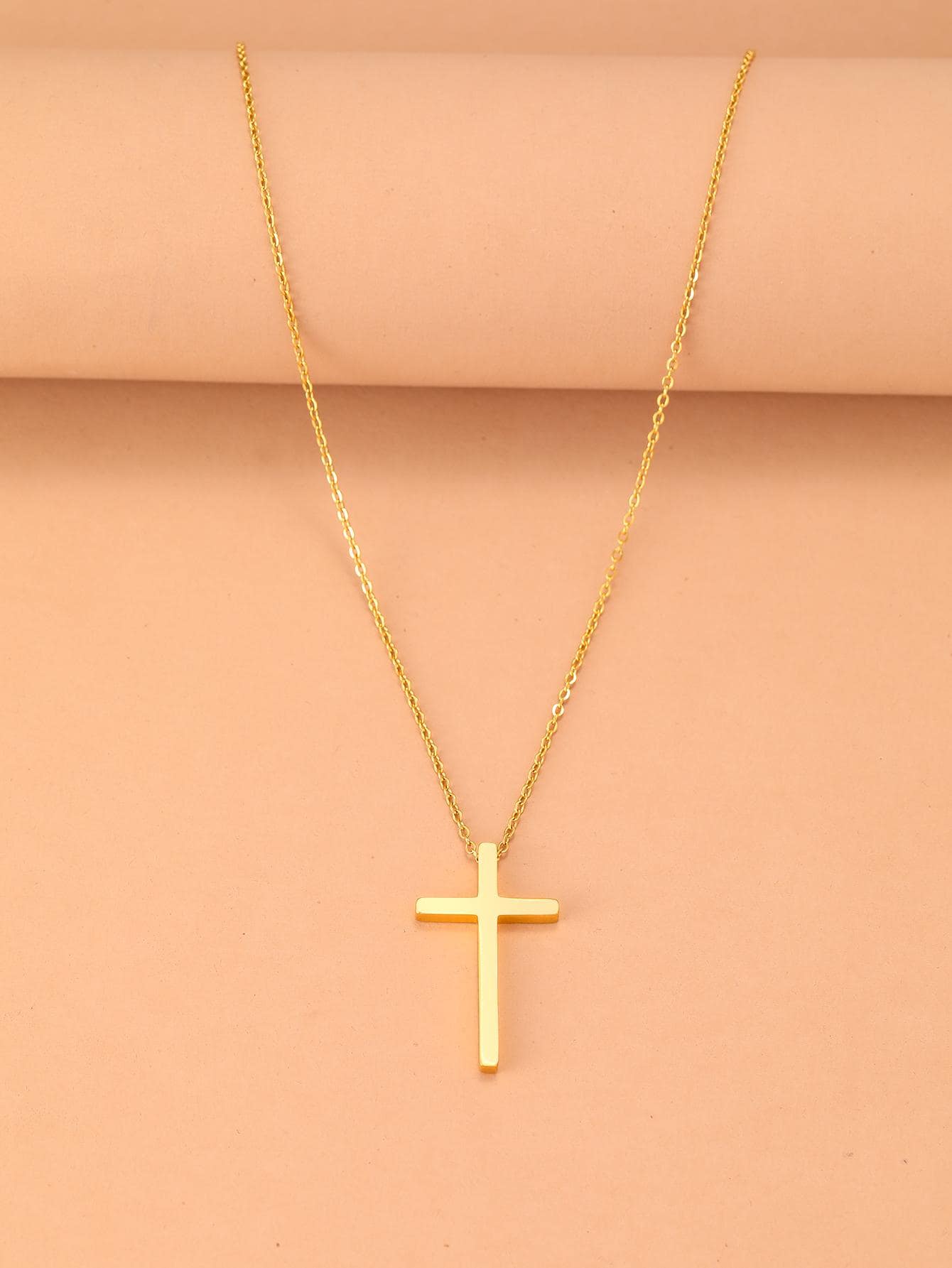 Gold cross necklace on a beige background