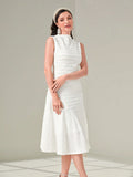 Woman wearing a white dress with a textured pattern on a light gray background