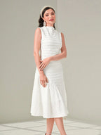 Woman wearing a white dress with a textured pattern on a light gray background