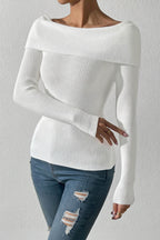 Person wearing a white sweater and blue jeans against a plain background