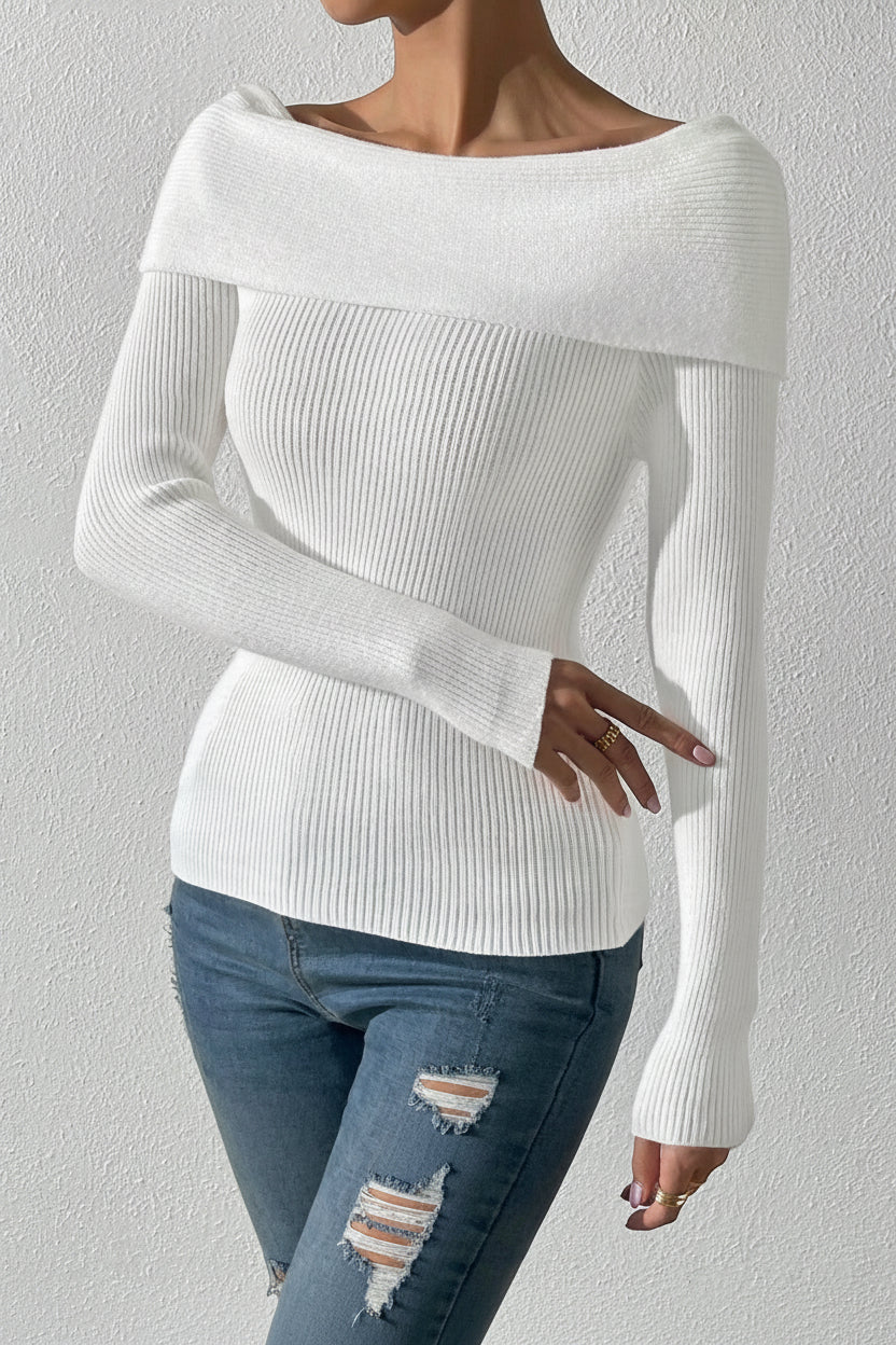 Person wearing a white sweater and blue jeans against a plain background