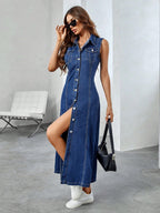 Woman wearing a blue denim dress with a slit, standing in a modern indoor setting.