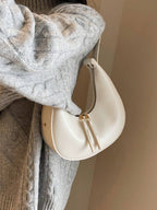 Beige handbag hanging on a hook with a gray sweater next to it.