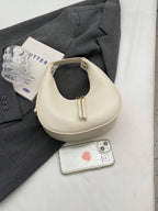 Beige handbag on a gray suit with a phone and glass of water
