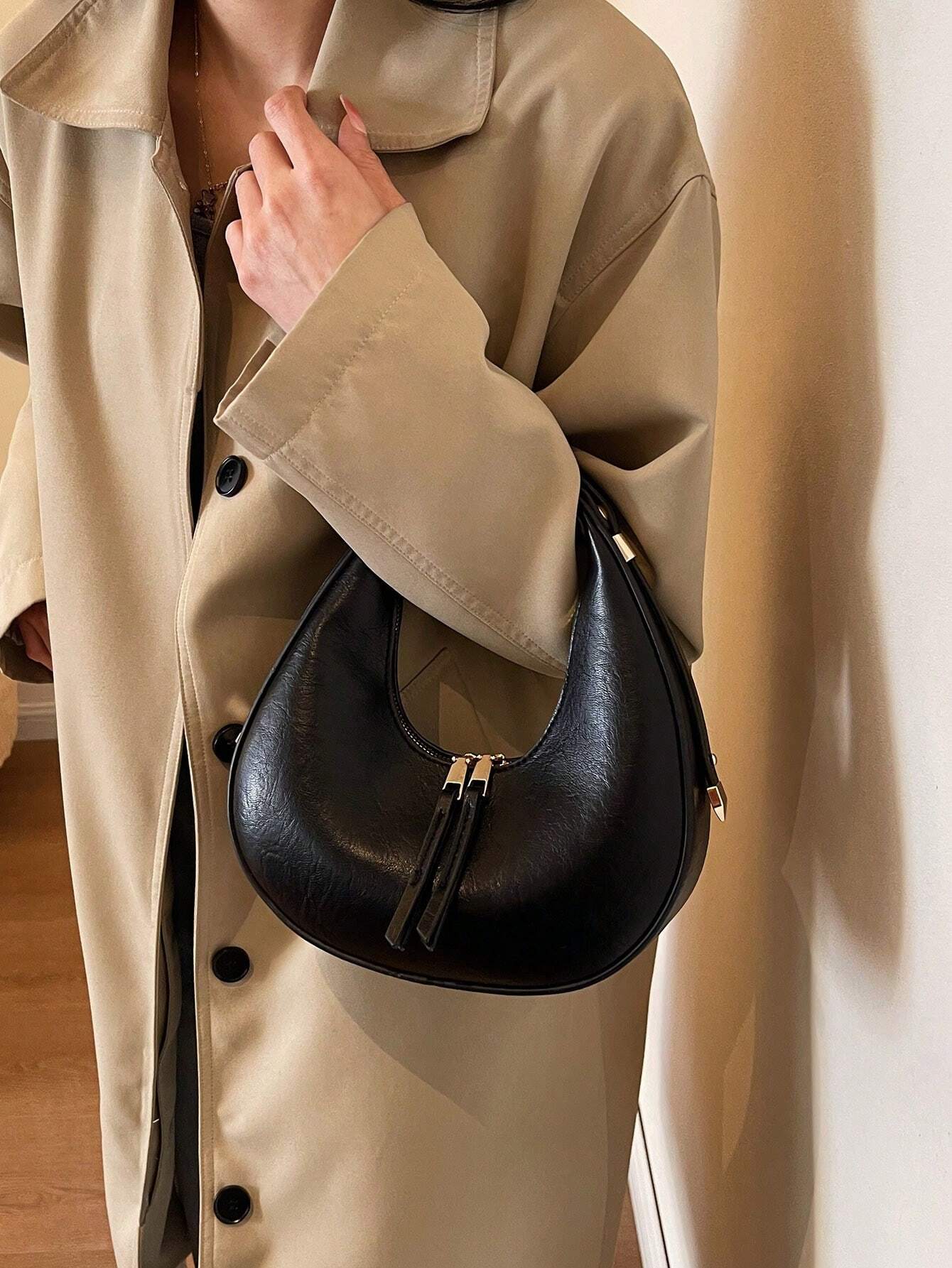 Person wearing a beige trench coat holding a black handbag.