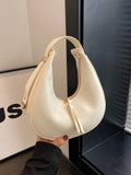 Beige handbag held by a person in front of a black and white background