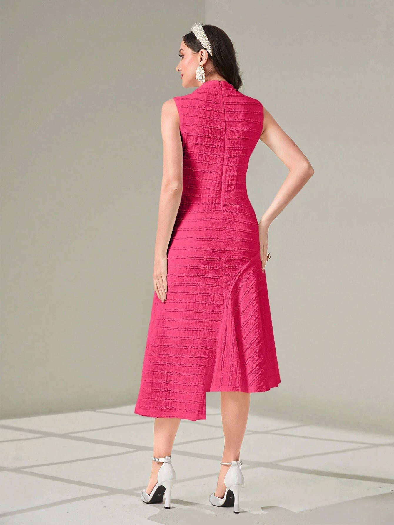 Woman wearing a pink dress with a textured pattern on a gray background