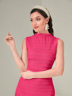 Woman wearing a pink dress with a tiara and earrings on a plain background
