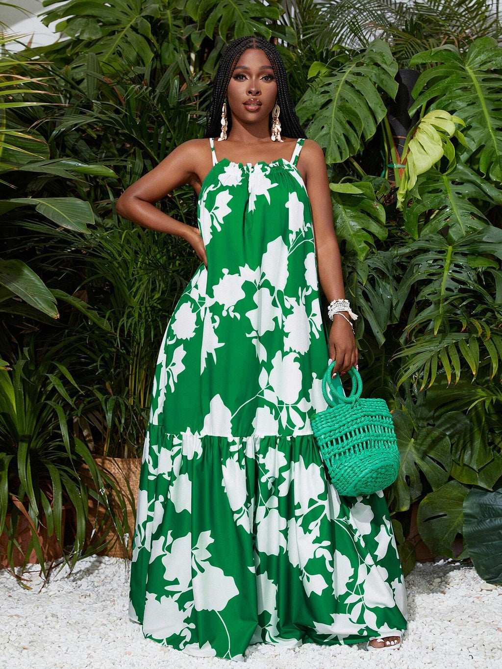 Woman in a green floral dress holding a green handbag amidst green plants.