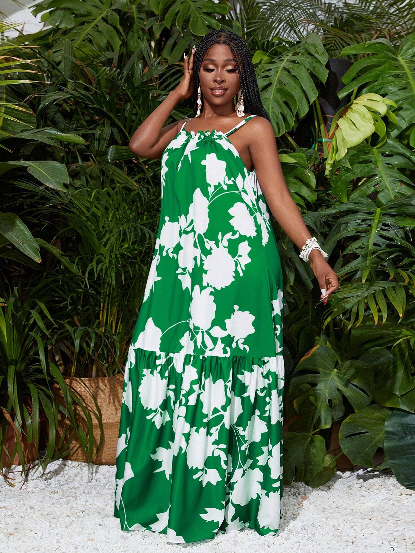 Woman wearing a green and white floral dress standing in front of green foliage.
