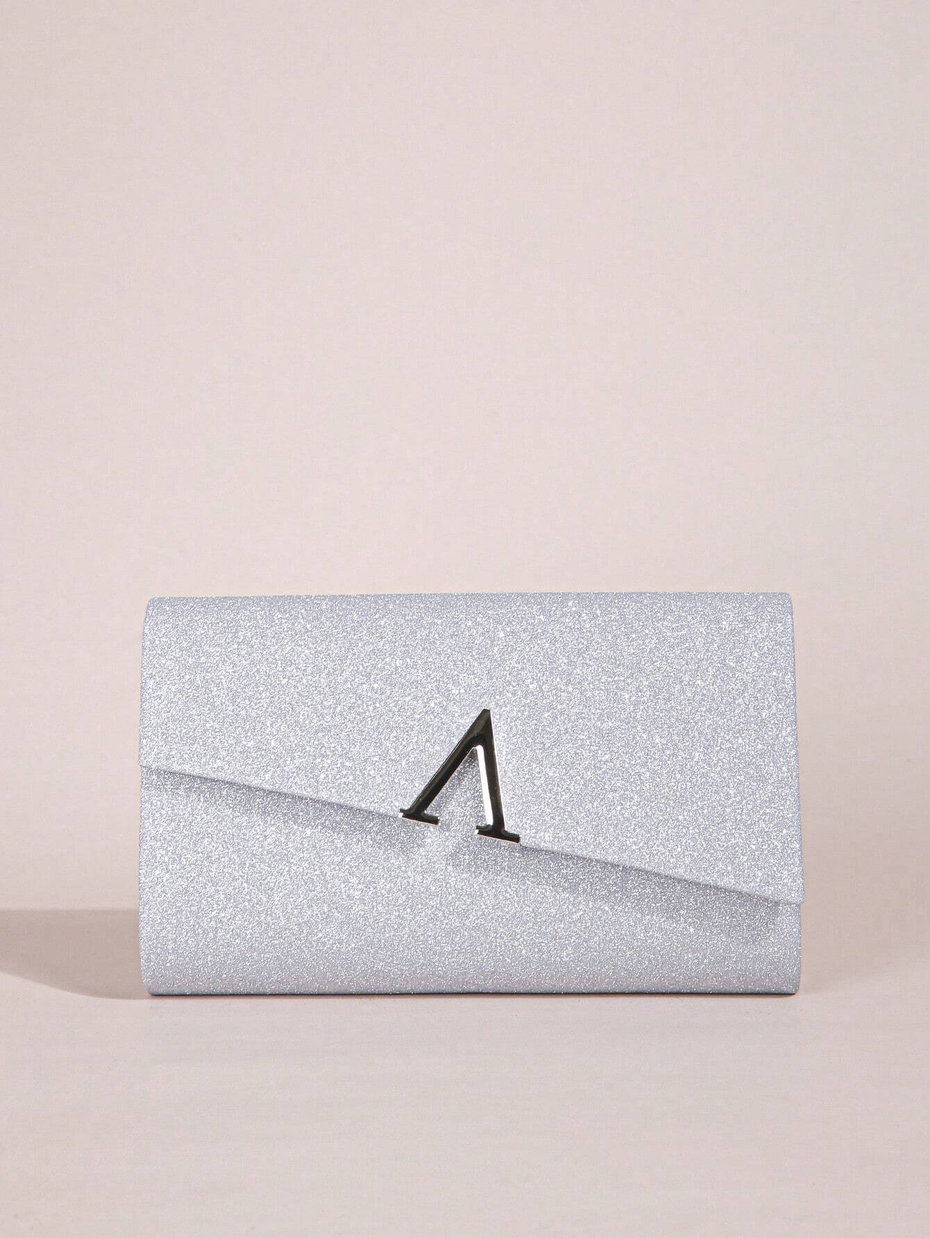 Silver glitter clutch bag with a black clasp on a beige background