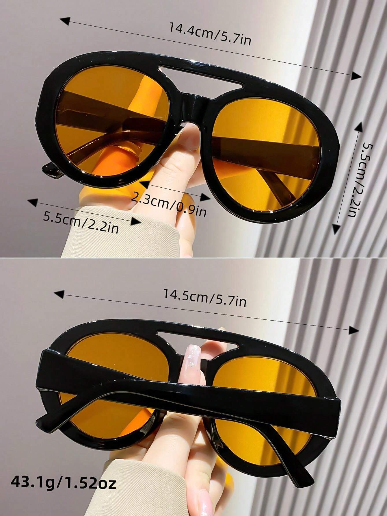 Sunglasses with yellow lenses held by a hand, showing measurements on a neutral background.
