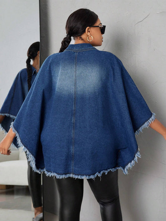 Woman wearing a blue denim poncho against a gray wall.