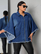 Woman wearing a blue denim poncho against a gray wall.